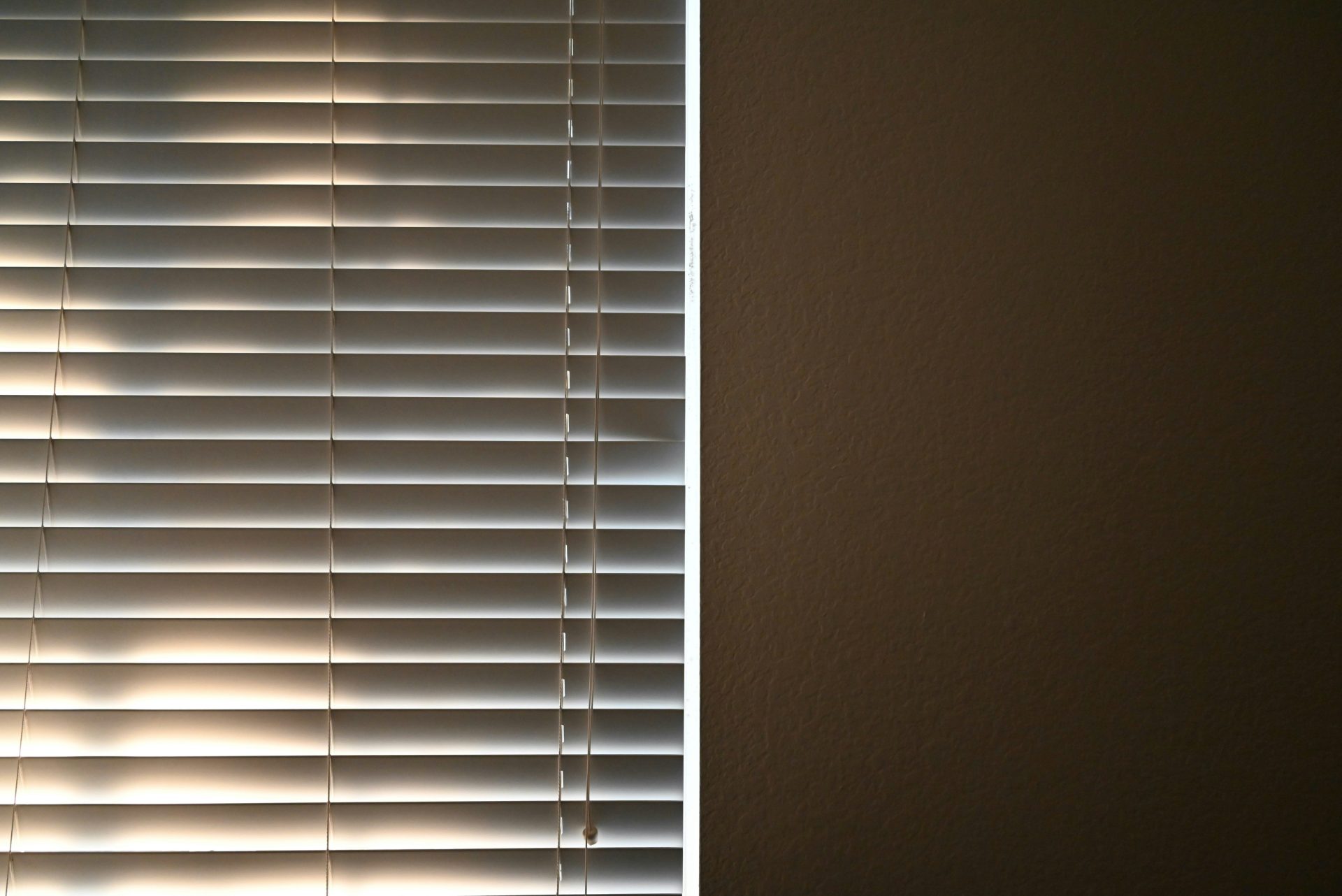 A window covered in blinds with a cloud in the background
